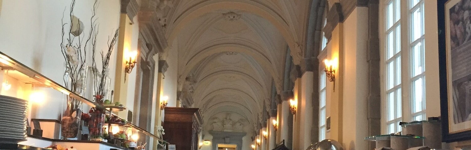 A grand hall with high ceilings, arched windows, and ornate wall decorations.