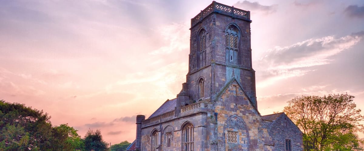 A historic stone church with a tall bell tower and arched windows.
