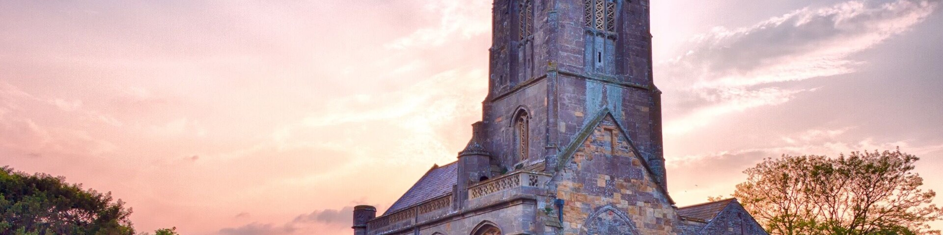 A historic stone church with a tall bell tower and arched windows.