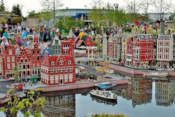 Ein Modell einer niederländischen Stadt mit roten und weißen Gebäuden, einem Kanal und einem kleinen Boot.