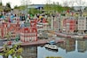 A model of a Dutch town with red and white buildings, a canal, and a small boat.