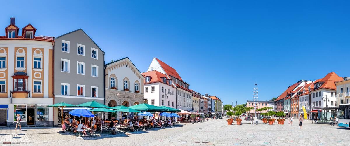 A cobblestone square with outdoor cafes, historic buildings, and a bus stop.