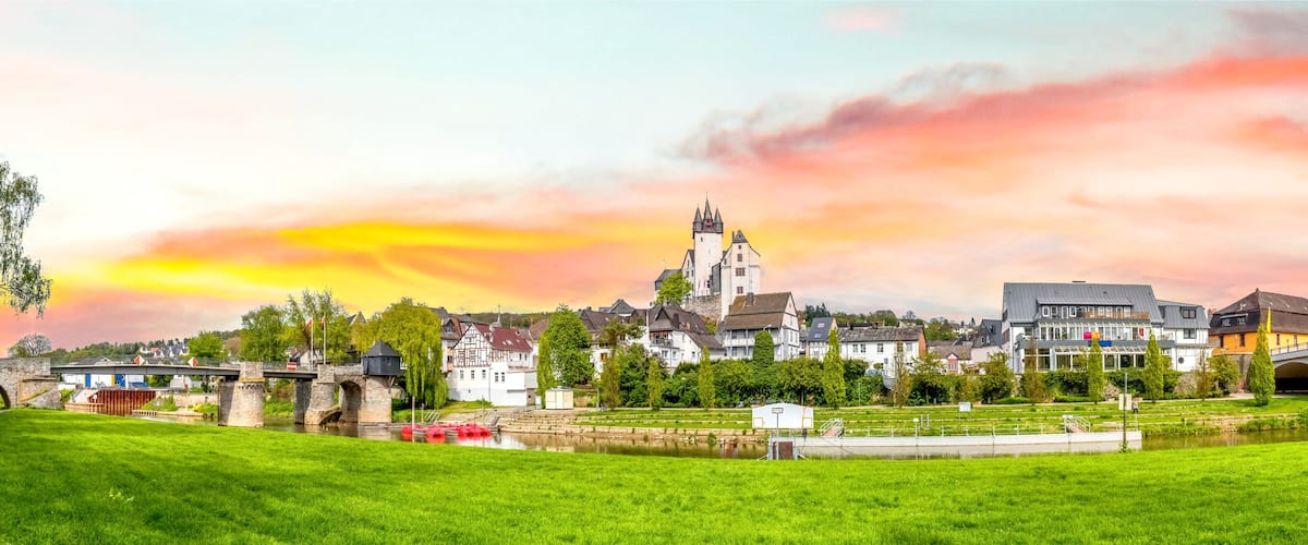 A picturesque town with a castle, a bridge, and a river.