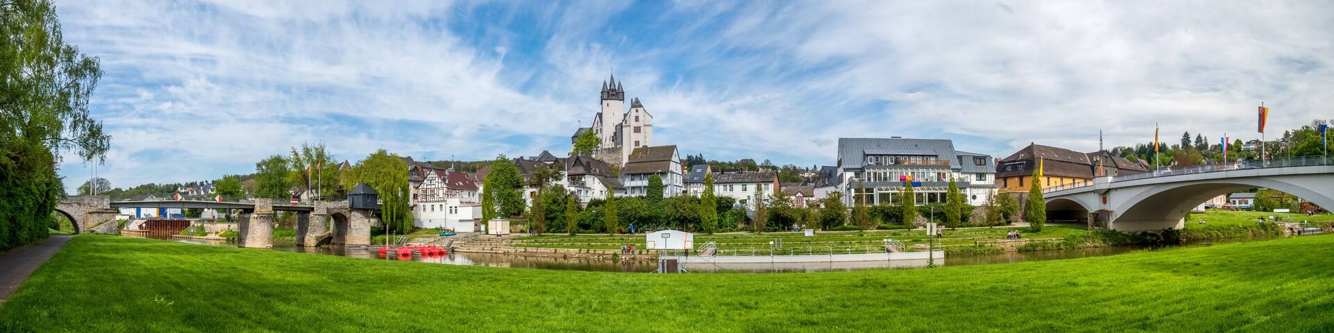 A historic town with a prominent castle, a river, and a stone bridge.