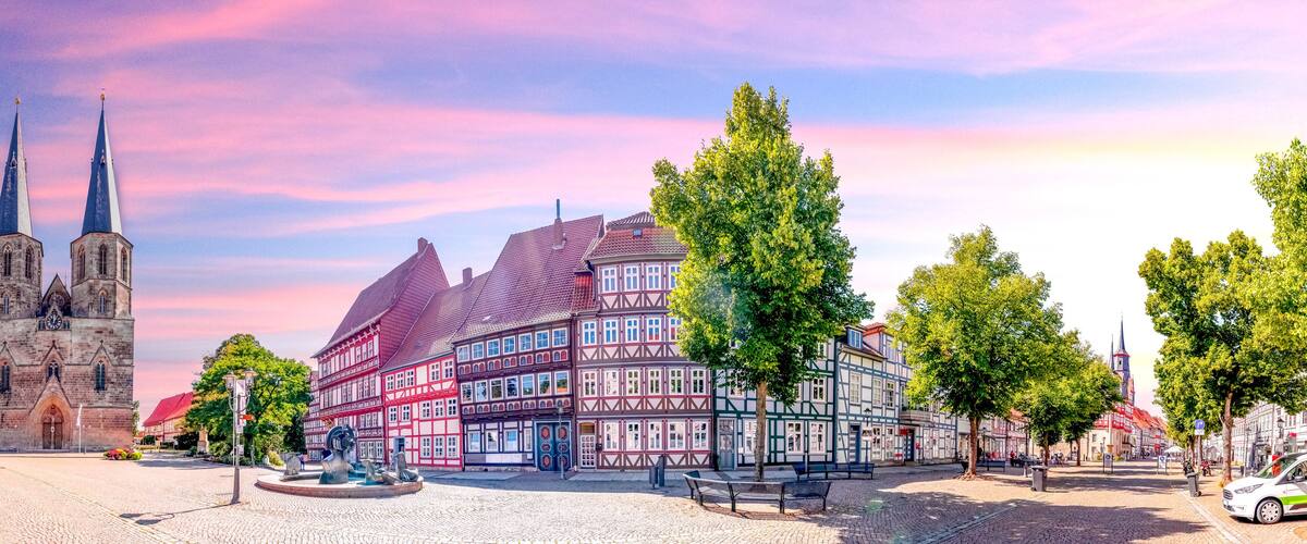 A historic town square with a church, traditional half-timbered houses, and a cobblestone street.