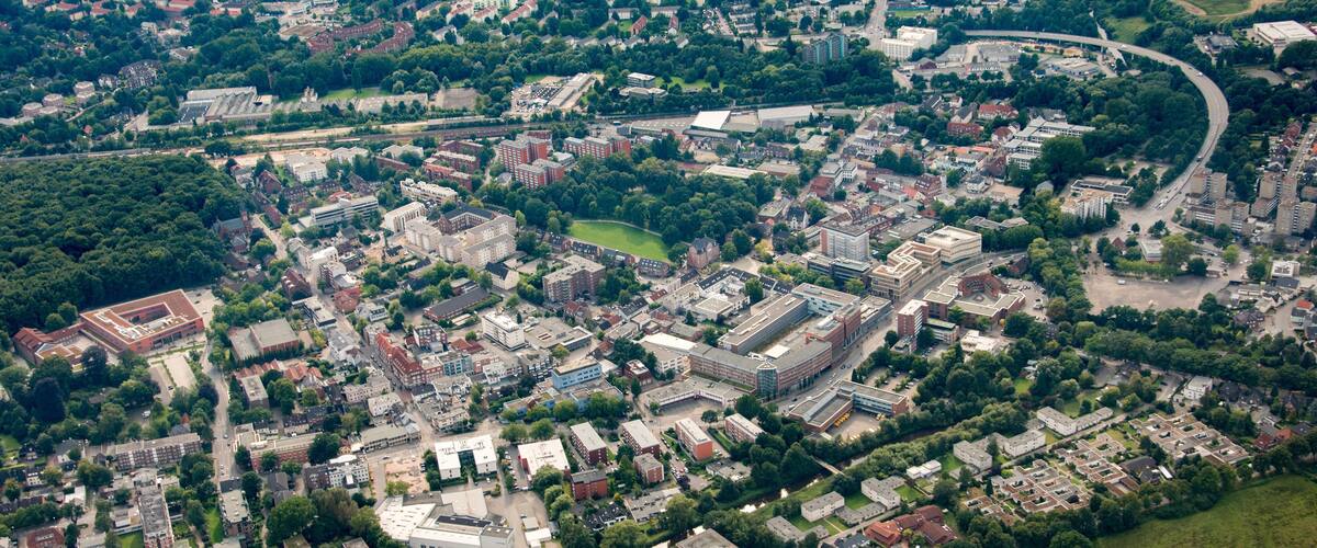 An aerial view of a city with dense urban areas, green spaces, and a river.
