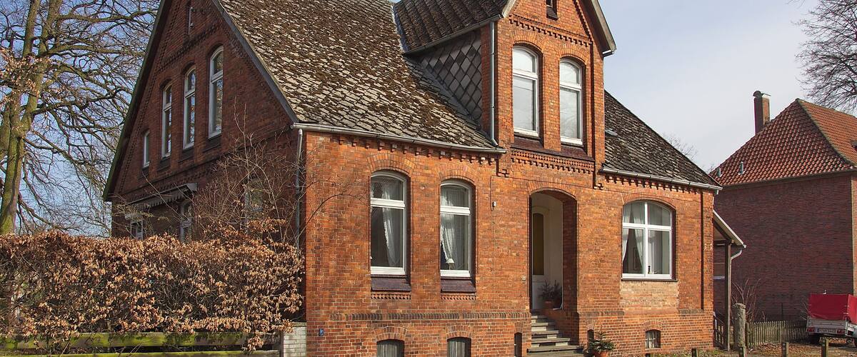 A red brick building with a steeply pitched roof and arched windows.