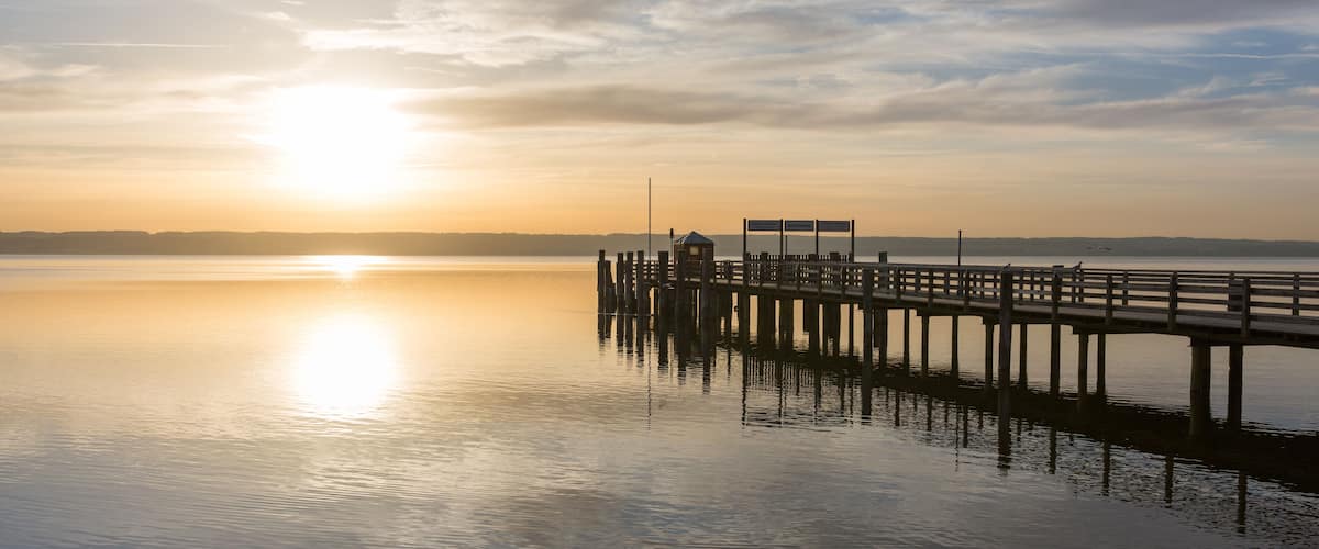 A pier extending into calm waters at sunrise with a clear sky.