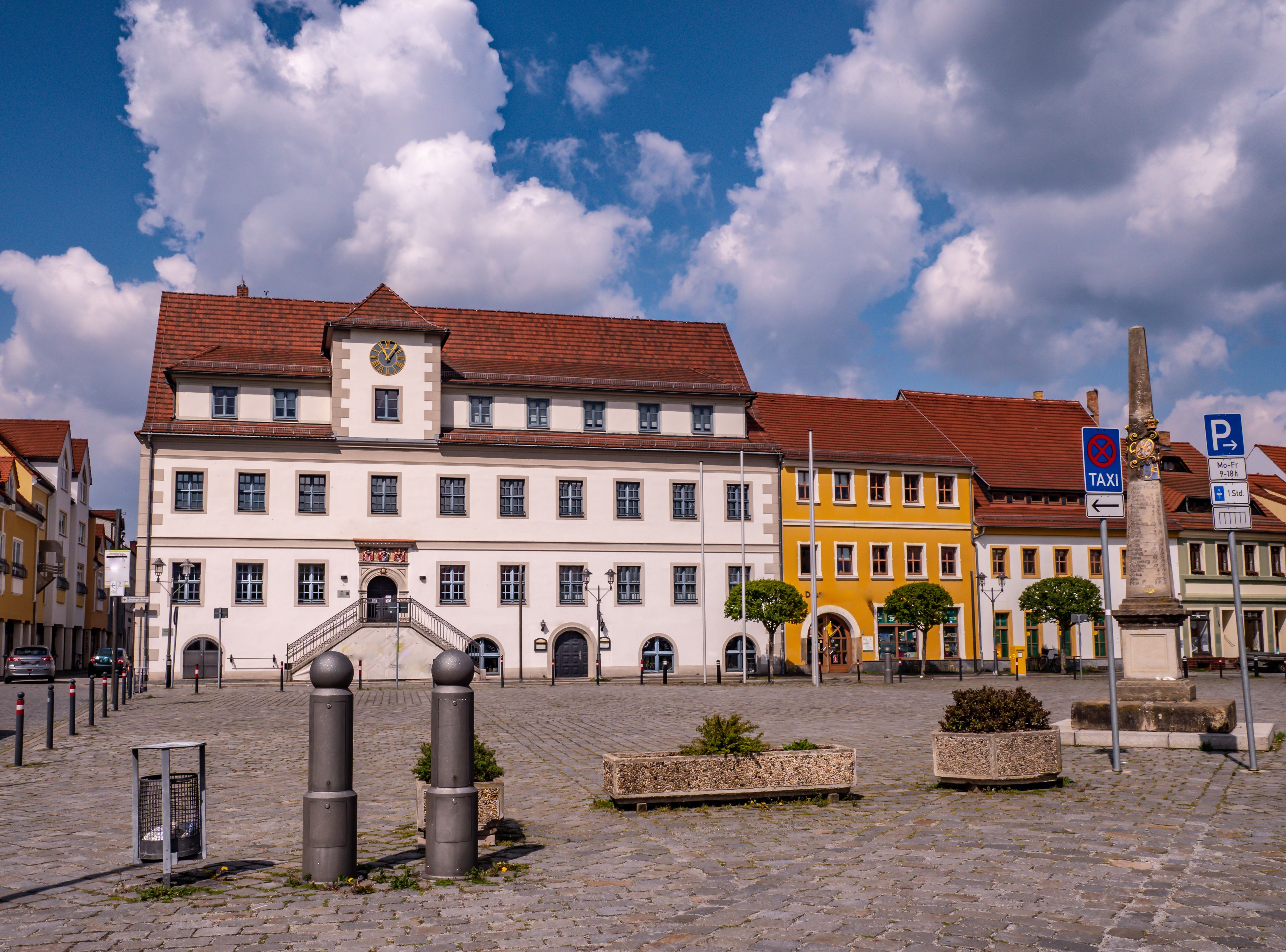 A historic building with a clock tower, cobblestone streets, and a statue.