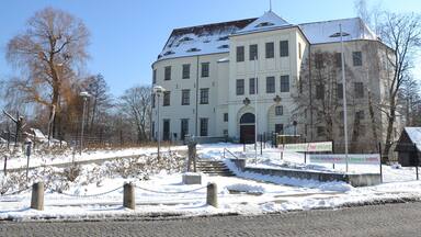 A large white building with multiple windows and a snow-covered roof.