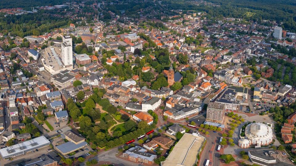 An aerial view of a densely populated city with a mix of residential and commercial buildings, a prominent church tower, and a round stadium.