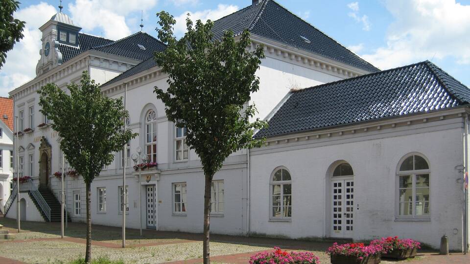 A historic building with a clock tower, white facade, and dark tiled roof.