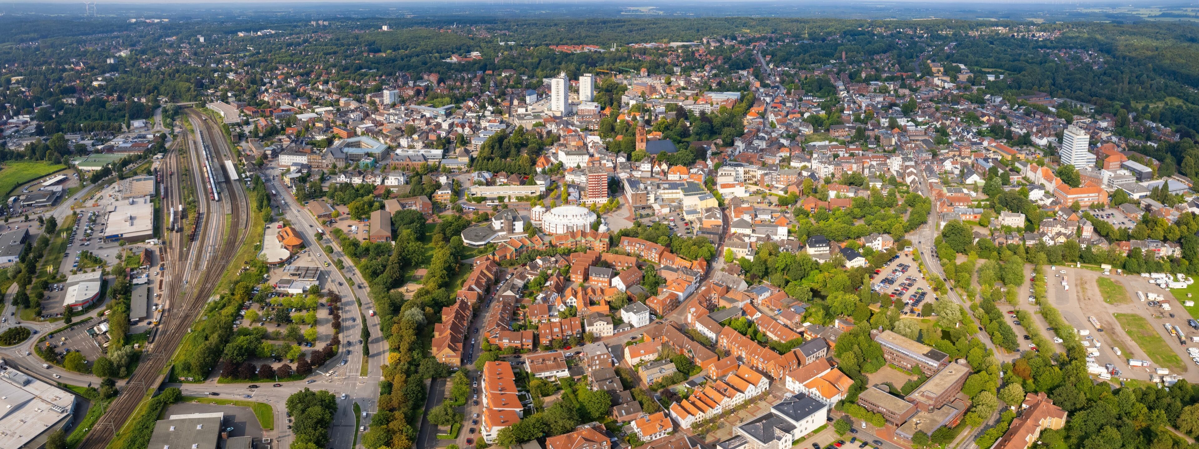 An aerial view of a city with a prominent train station, dense residential areas, and a mix of historical and modern architecture.