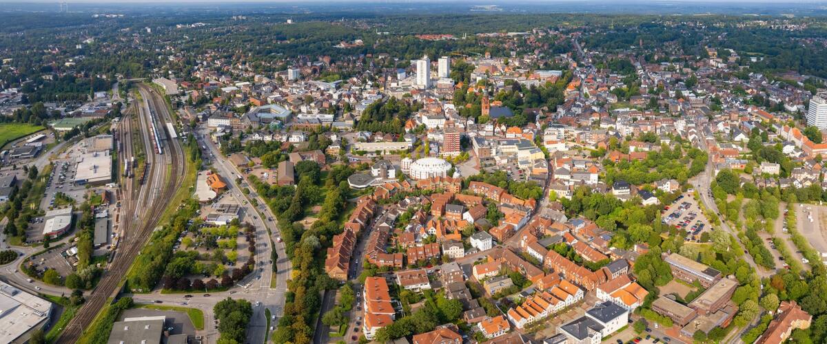An aerial view of a city with a prominent train station, dense residential areas, and a mix of historical and modern architecture.