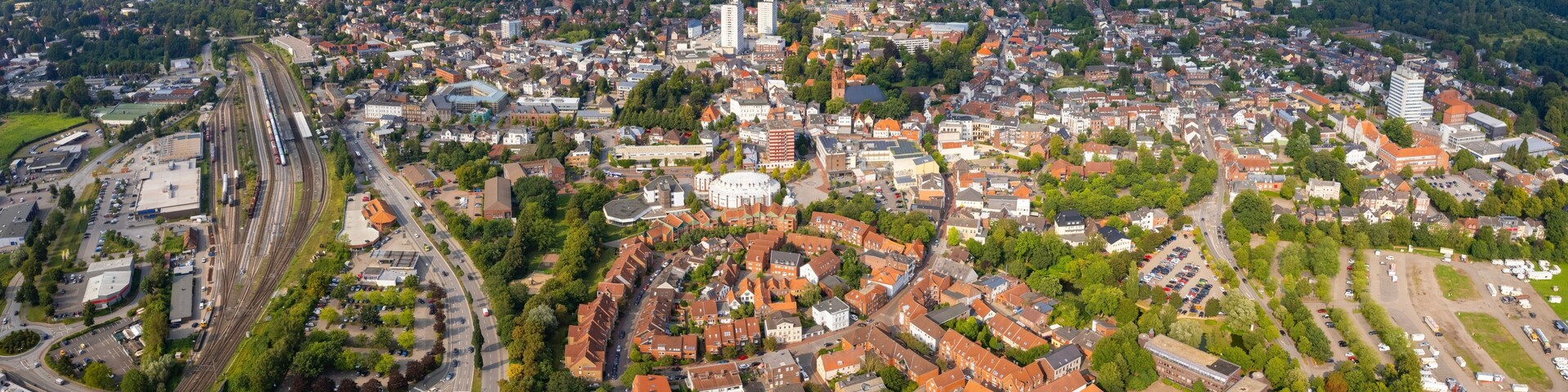 An aerial view of a city with a prominent train station, dense residential areas, and a mix of historical and modern architecture.