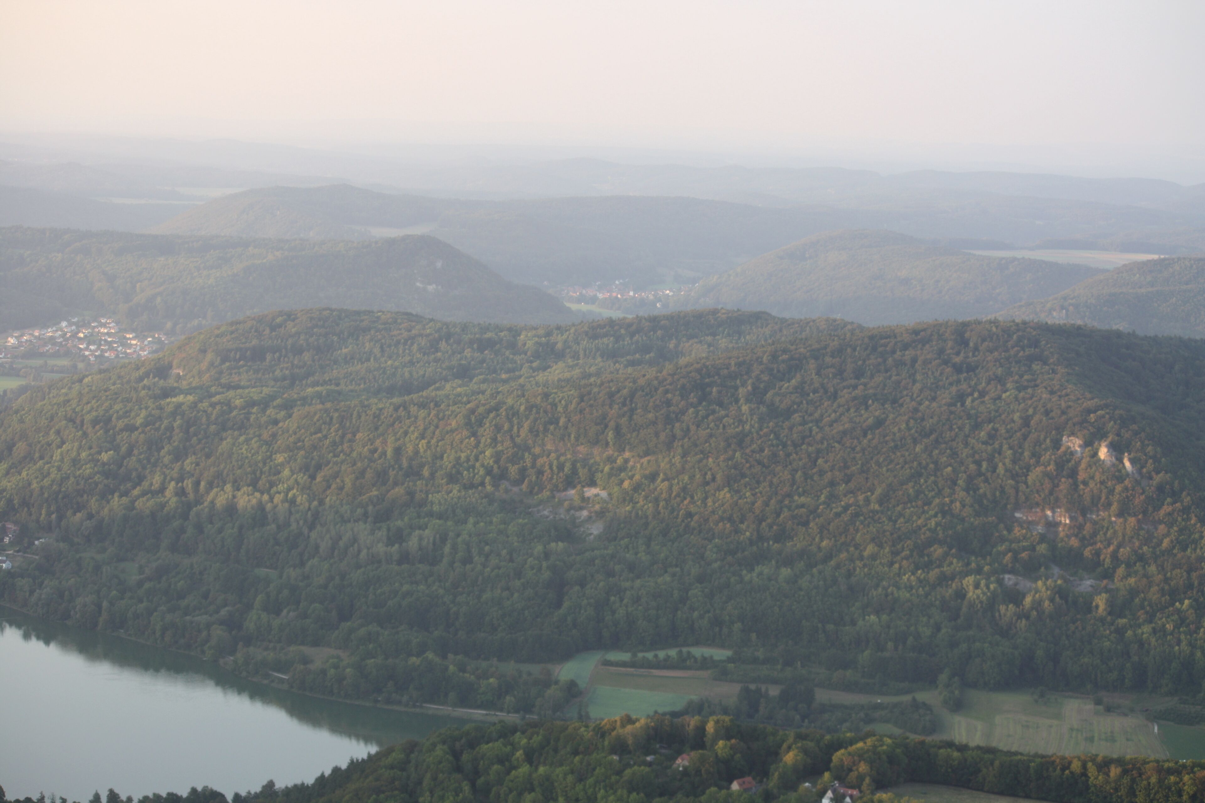 A mountainous landscape with a lake and scattered buildings.
