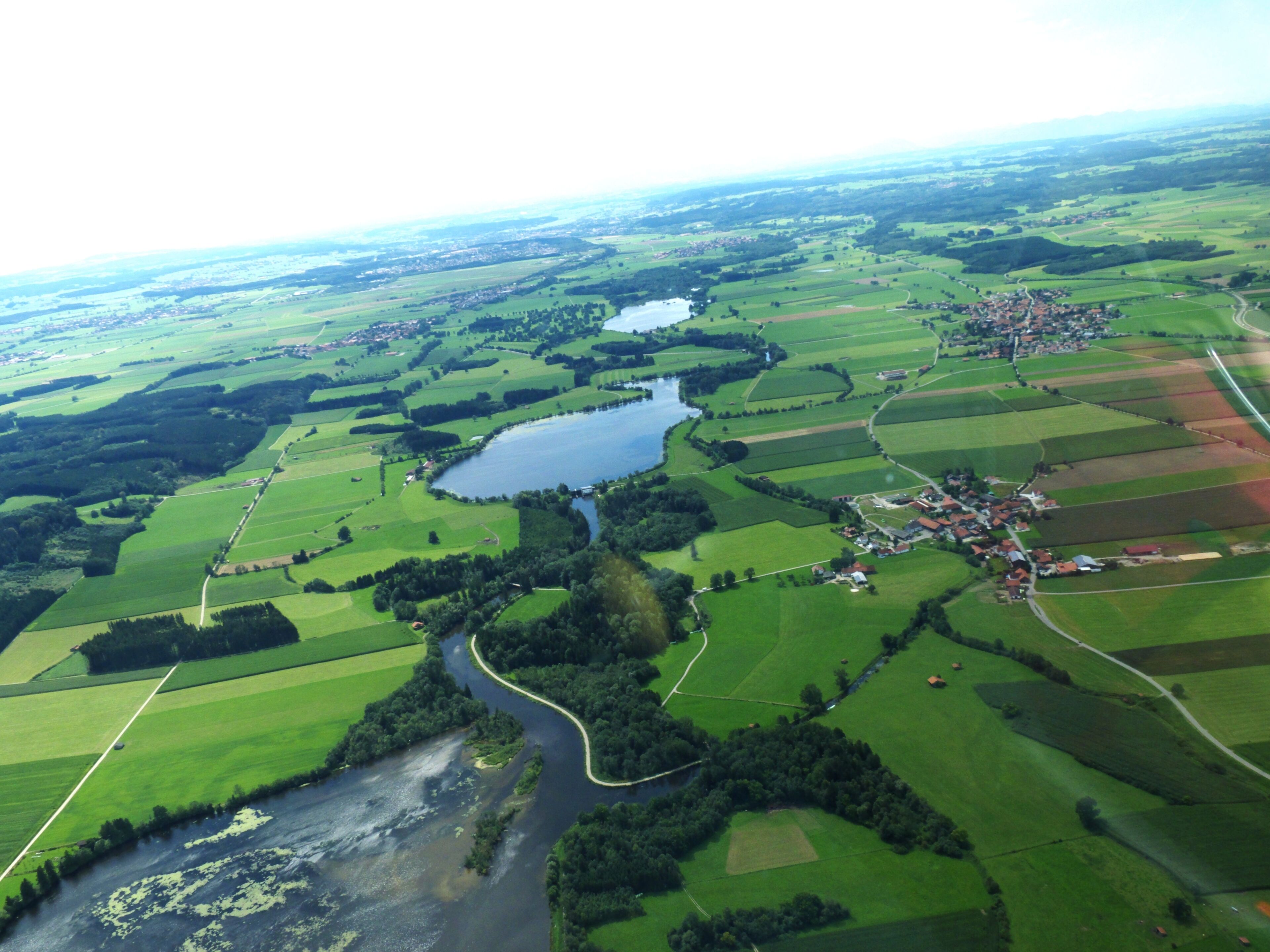 An aerial view of a river winding through green fields and a small village.
