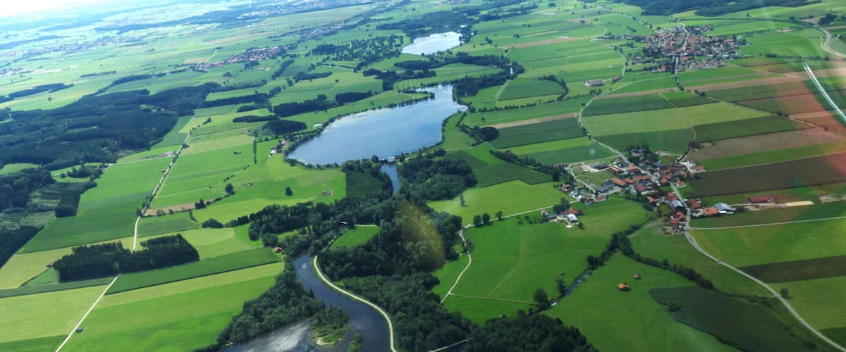 An aerial view of a river winding through green fields and a small village.