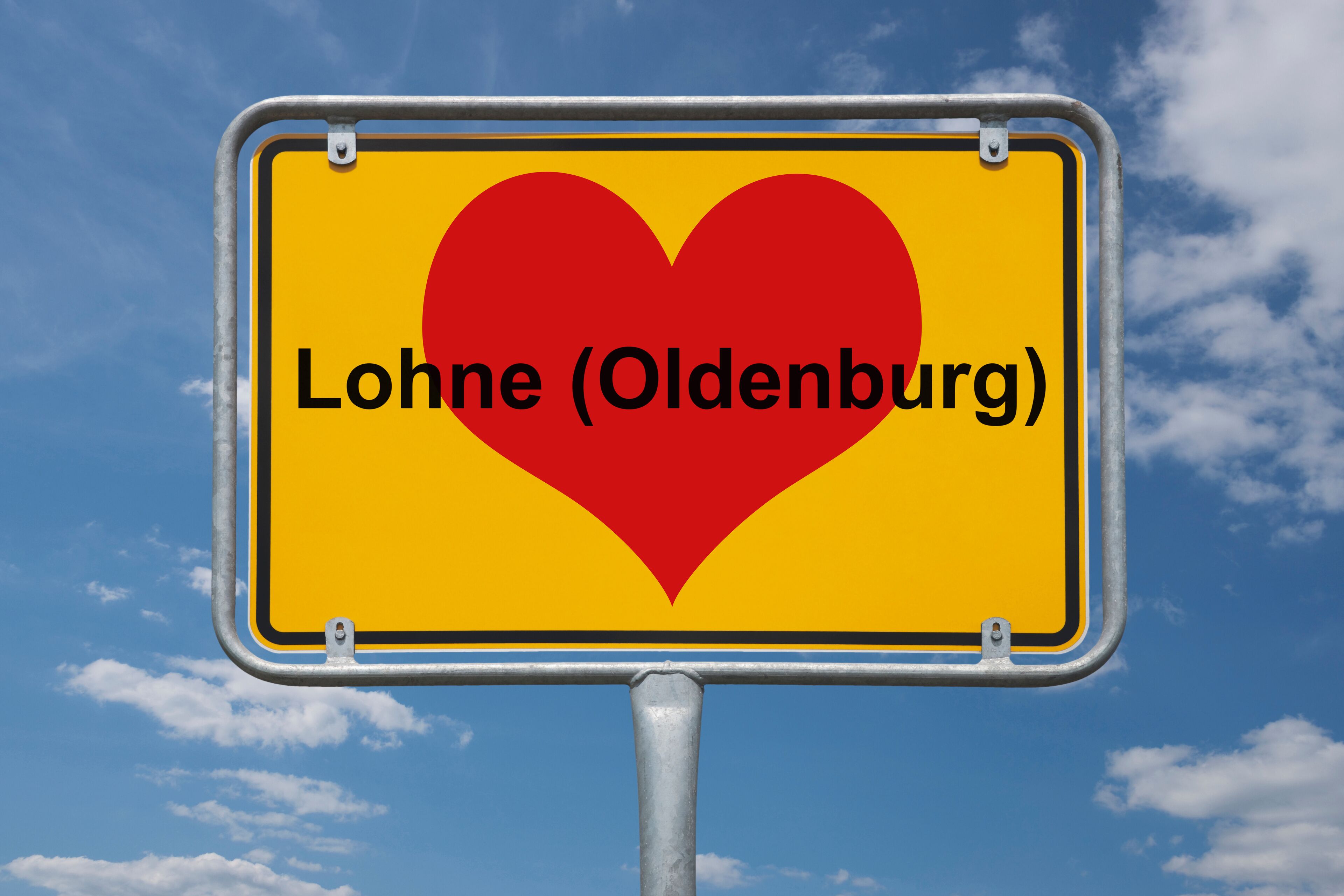 A yellow sign with a red heart and the text "Lohne (Oldenburg)" against a blue sky with clouds.