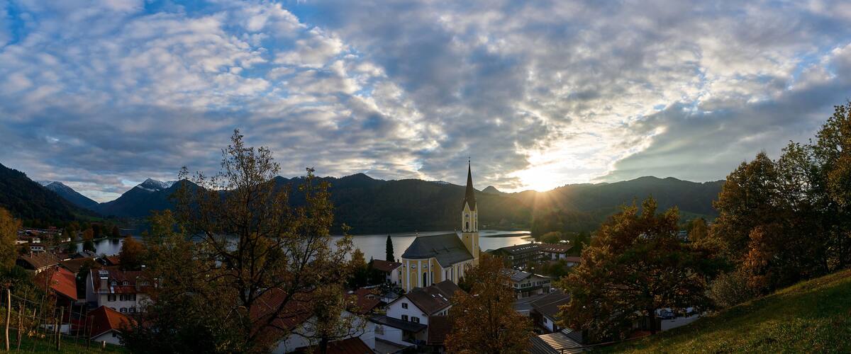 A town with a church, mountains, and a lake.