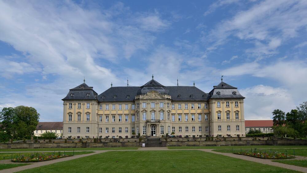 Un grand bâtiment historique à la façade symétrique, doté de nombreuses fenêtres et d’une entrée centrale.