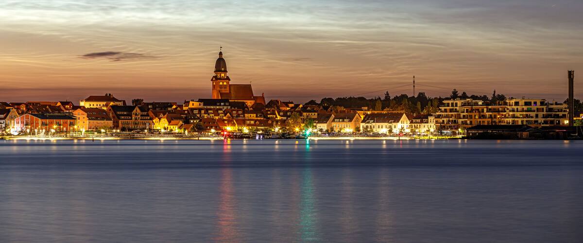Leuchtende Nachtwolken über der Stadt Waren (Müritz) mit der Marienkirche