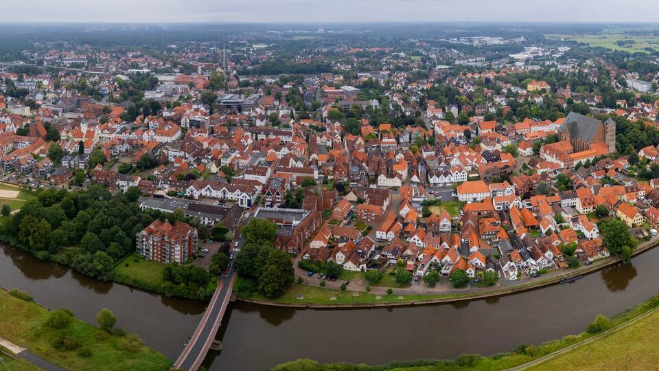 A river winding through a town with red-roofed buildings and green fields.