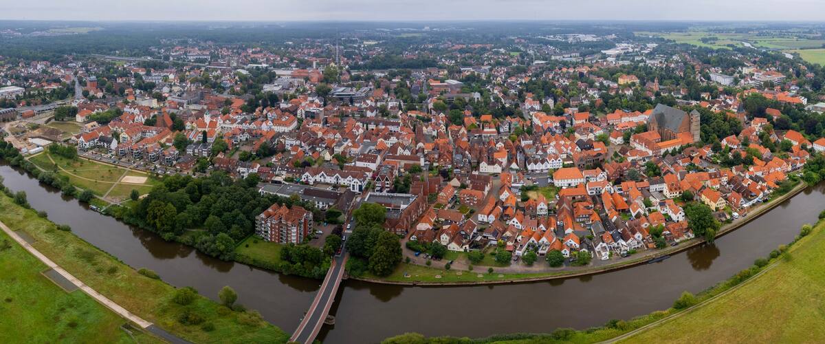 A river winding through a town with red-roofed buildings and green fields.