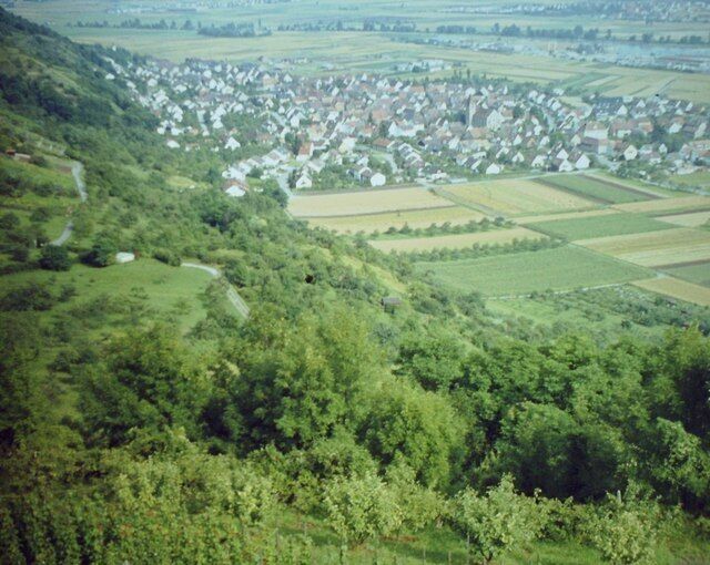 A village nestled in a valley surrounded by lush greenery and fields.