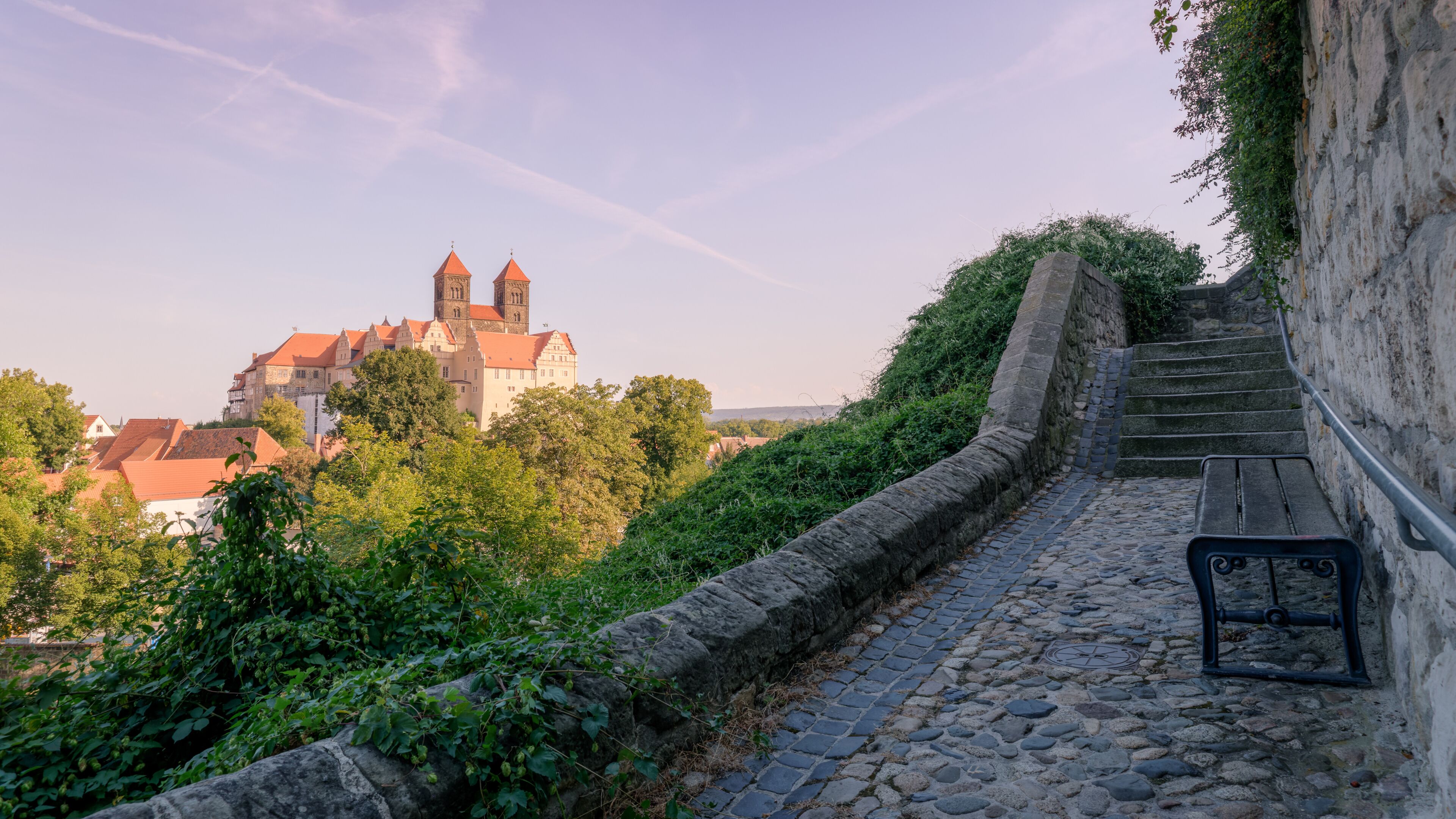 Quedlinburg, Germany – August 29, 2024: On a hot August night, sun is setting at the Collegiate Church of St. Servatii and the Quedlinburg Castle, part of the UNESCO World Heritage City Quedlinburg. 