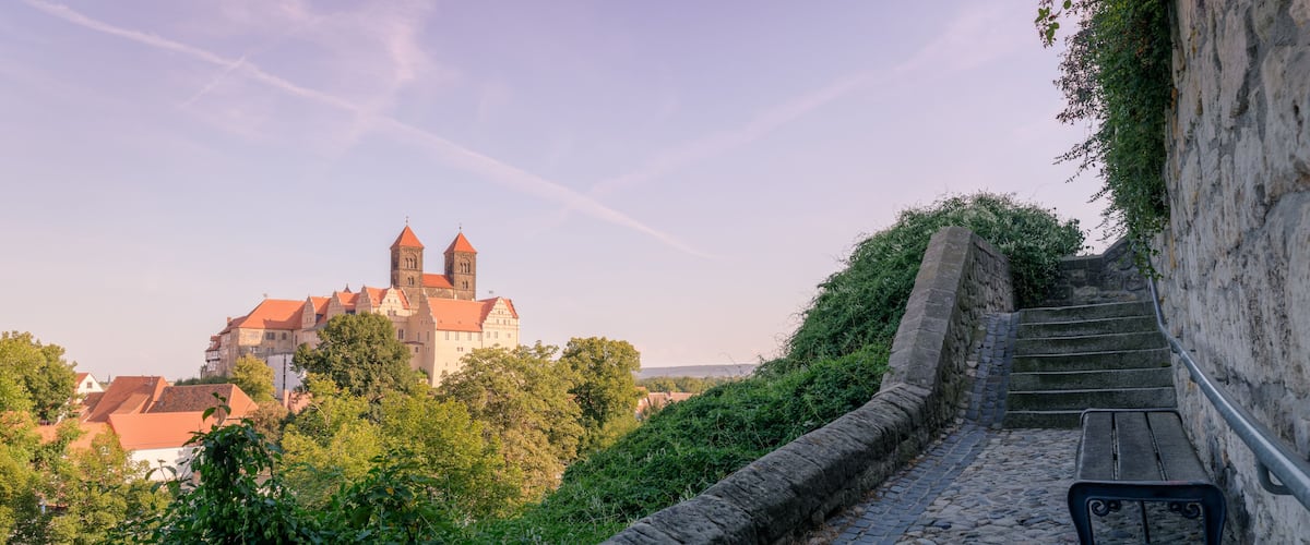 Quedlinburg, Germany – August 29, 2024: On a hot August night, sun is setting at the Collegiate Church of St. Servatii and the Quedlinburg Castle, part of the UNESCO World Heritage City Quedlinburg.