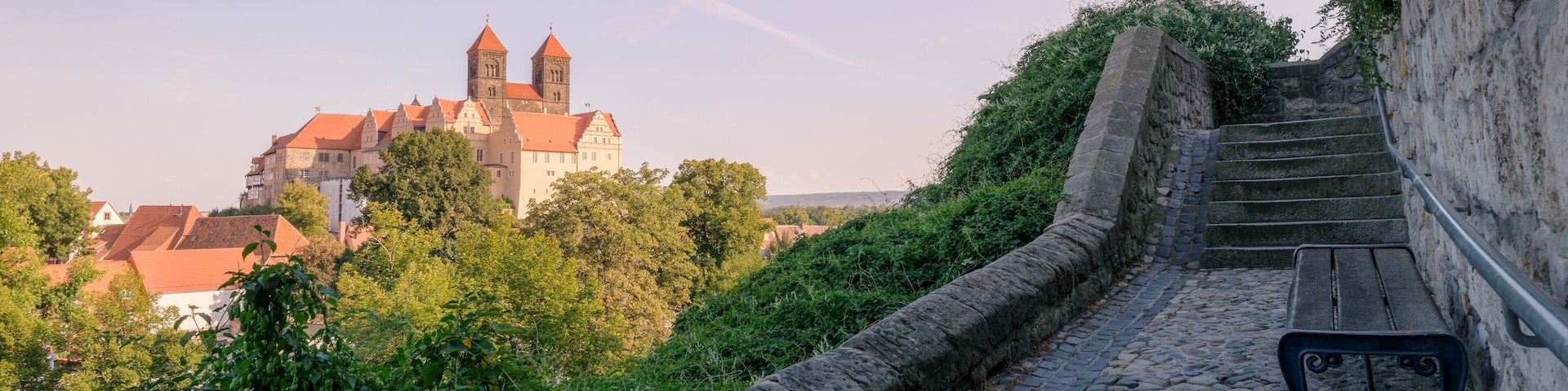 Quedlinburg, Germany – August 29, 2024: On a hot August night, sun is setting at the Collegiate Church of St. Servatii and the Quedlinburg Castle, part of the UNESCO World Heritage City Quedlinburg.