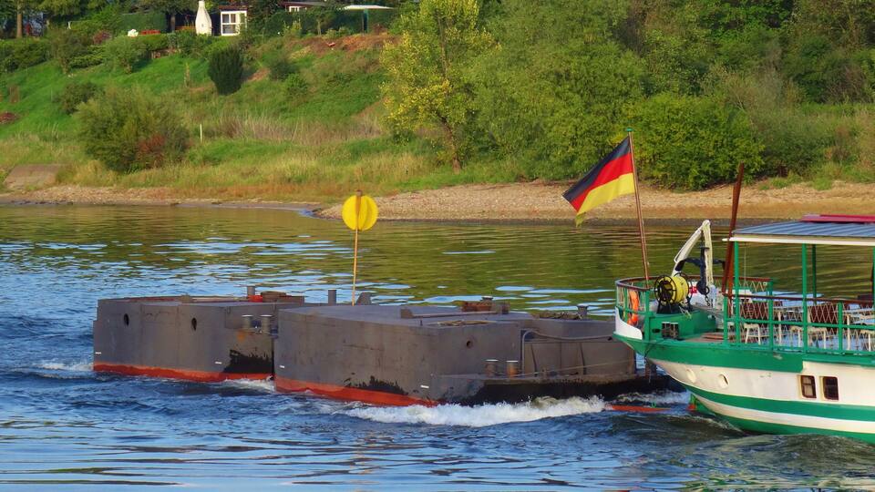 A green and white boat with a German flag on the water.