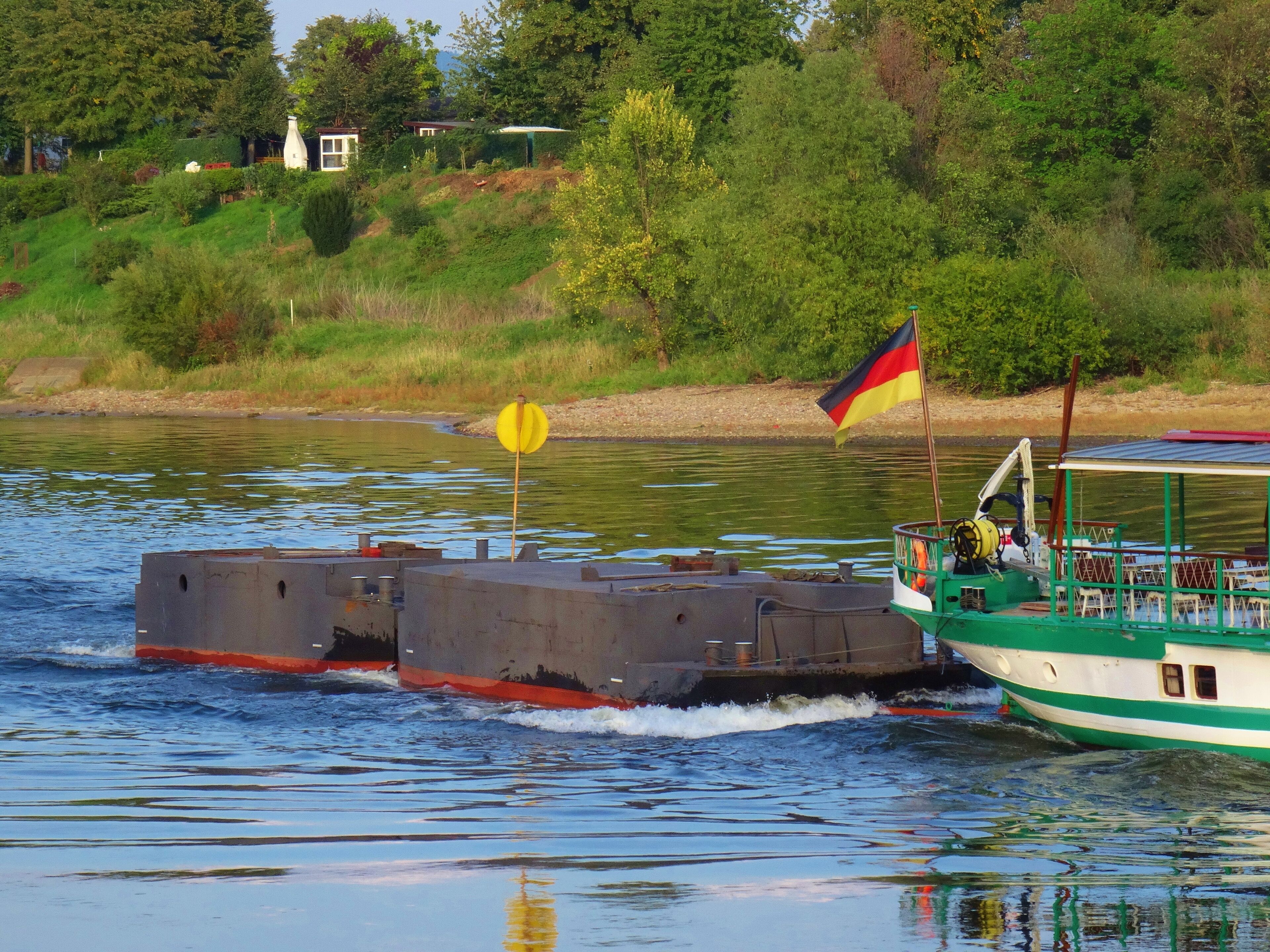 A green and white boat with a German flag on the water.