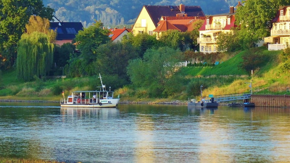A river with a boat, houses, and a bridge.