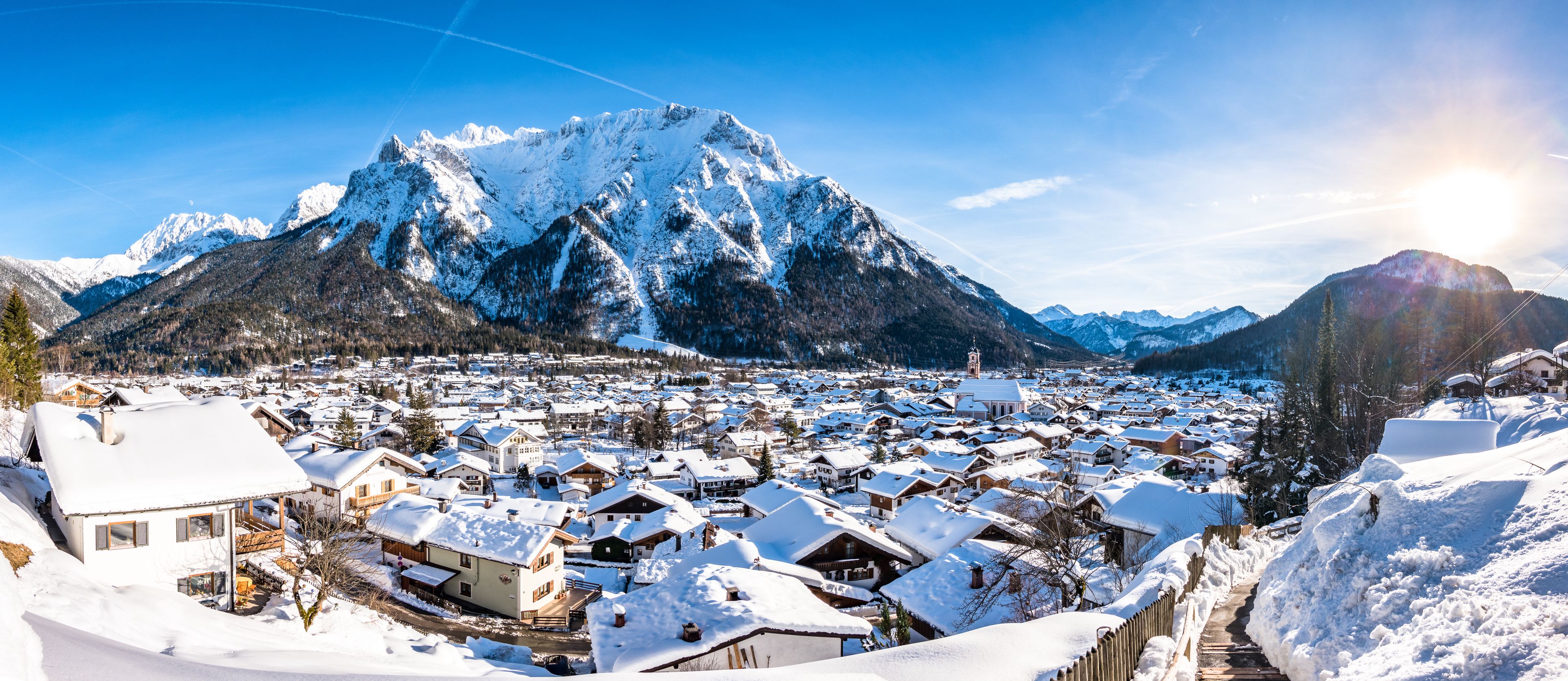 A snow-covered village with houses and a mountain in the background.