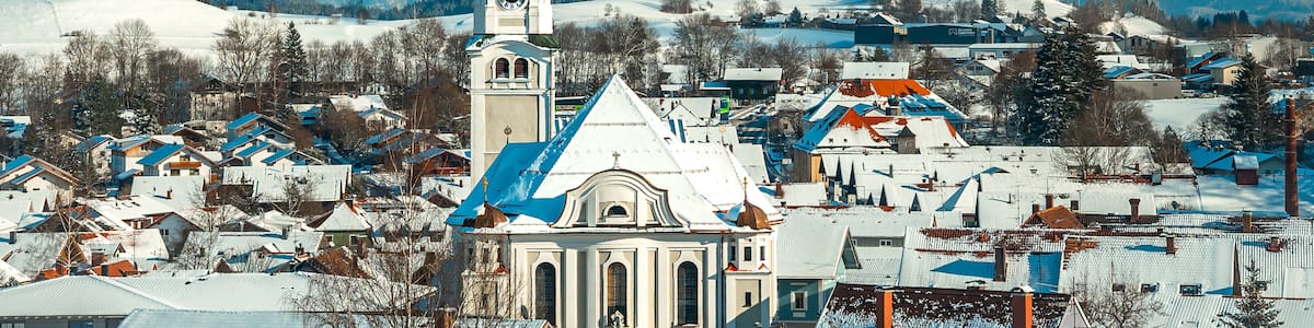 A snow-covered town with a prominent church and mountains in the background.