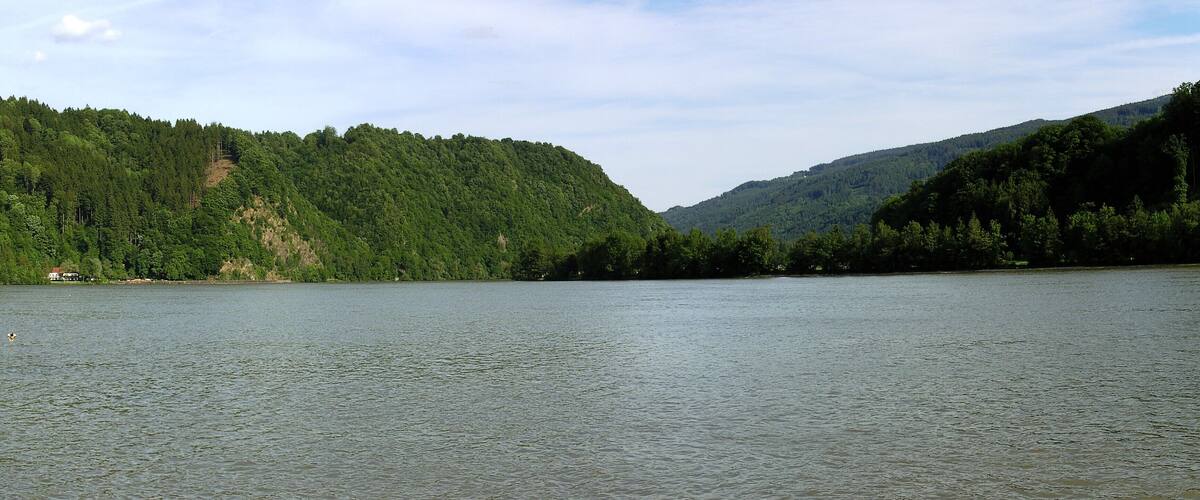 A calm lake surrounded by dense forests and hills.
