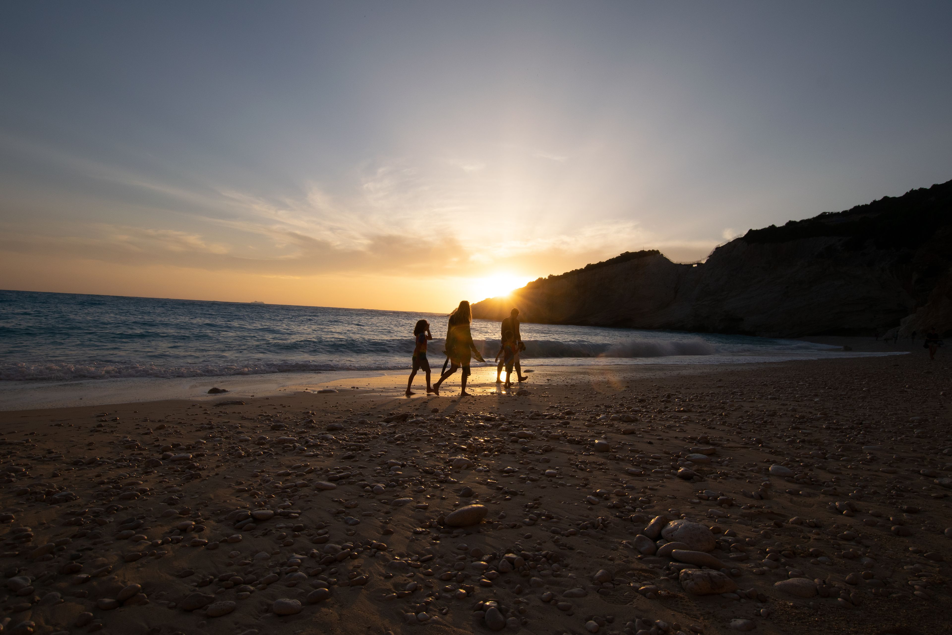 Una playa con gente caminando por la orilla al atardecer.