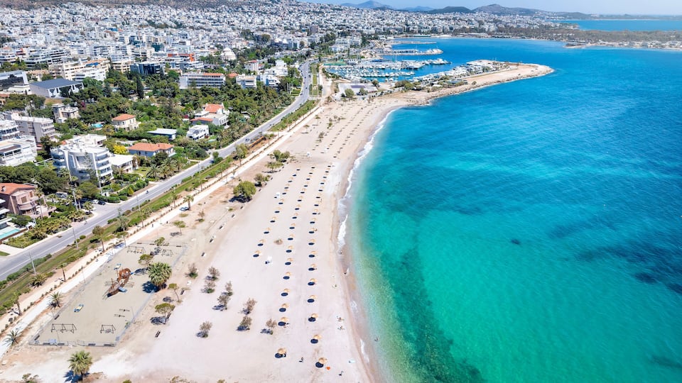 A coastal cityscape with a long sandy beach, a marina, and dense urban buildings.