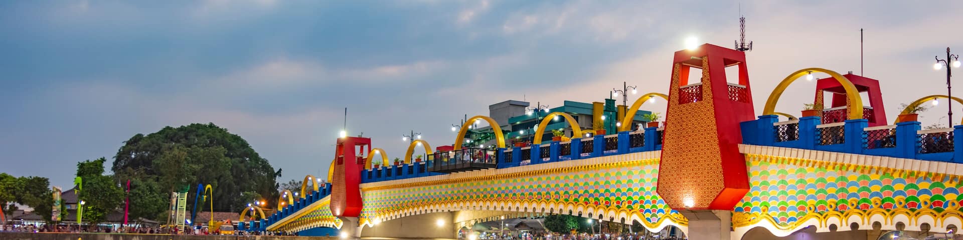 A brightly lit bridge with colorful patterns and arches over a body of water.