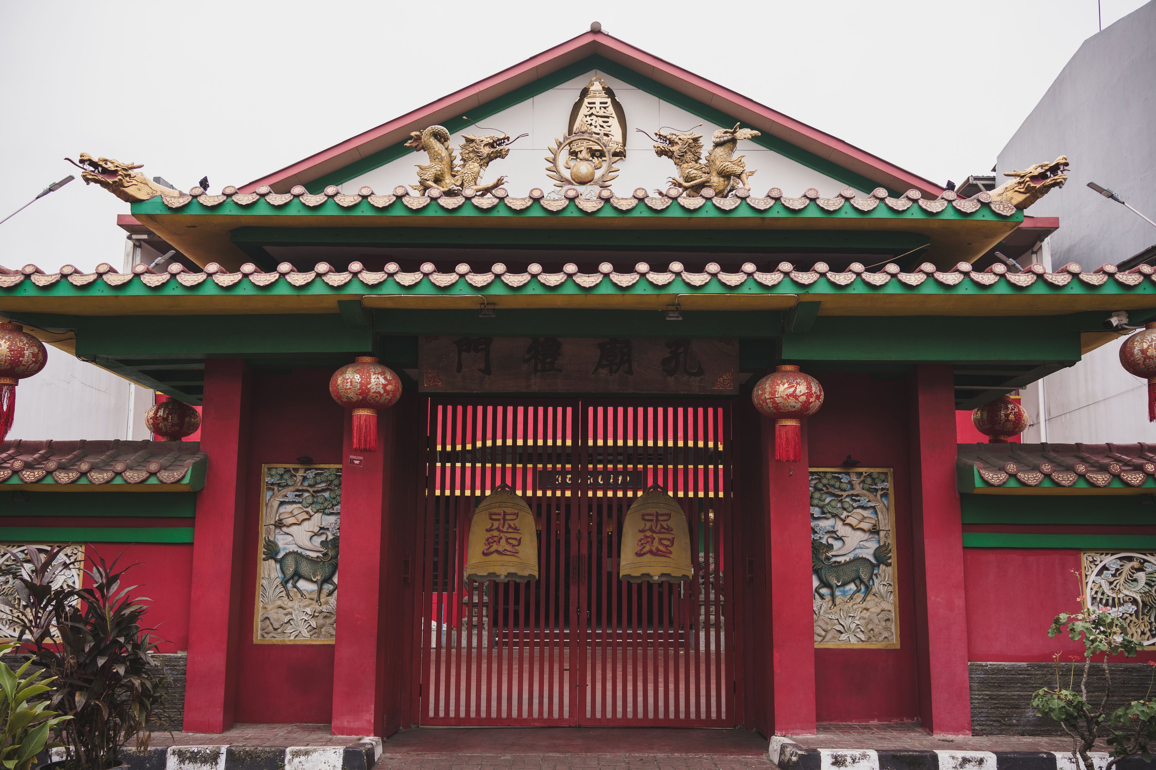A traditional Chinese gate with red and green colors, ornate dragon sculptures, and a tiled roof.