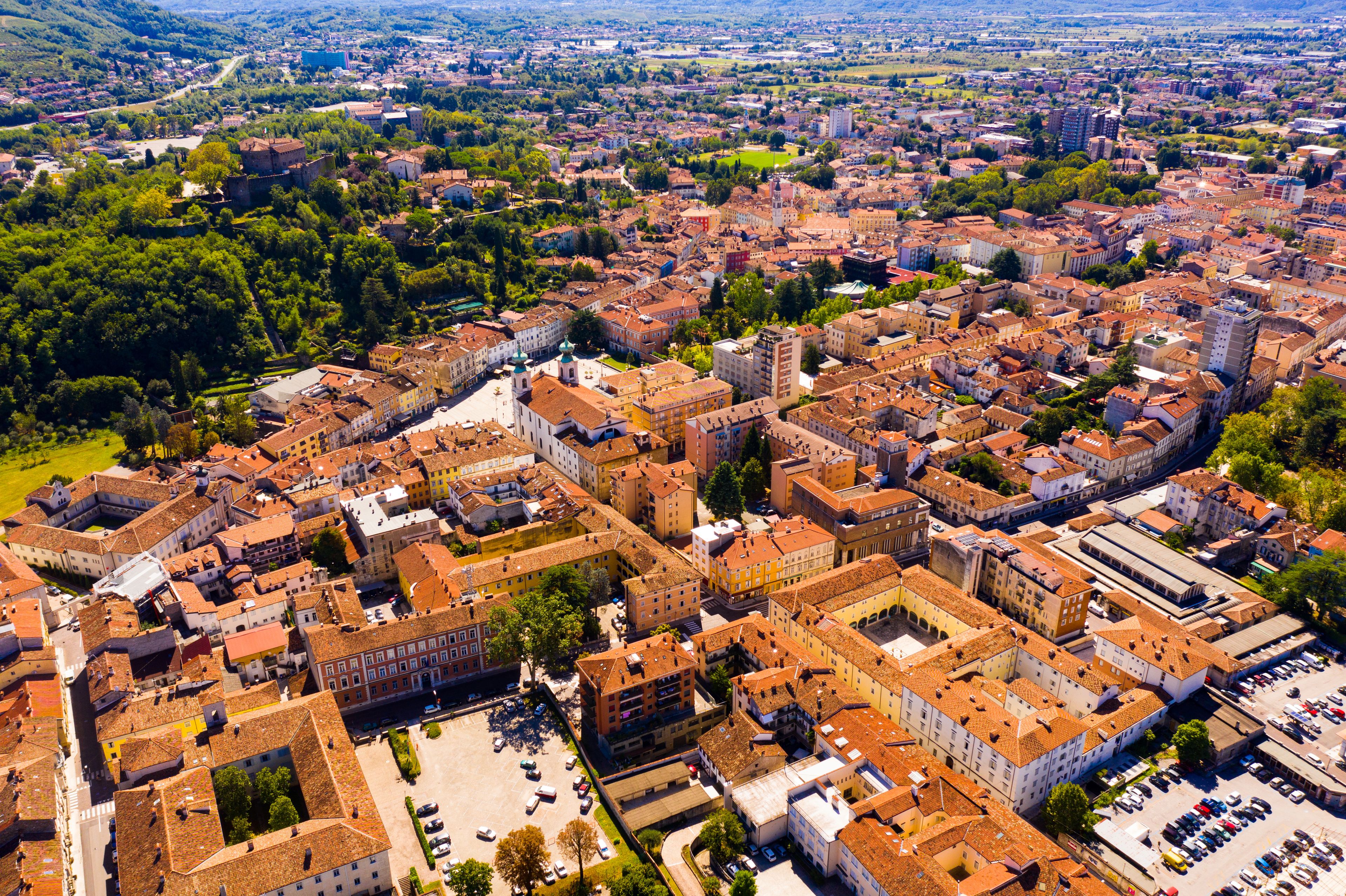A densely packed urban area with historic architecture, surrounded by lush greenery and hills.