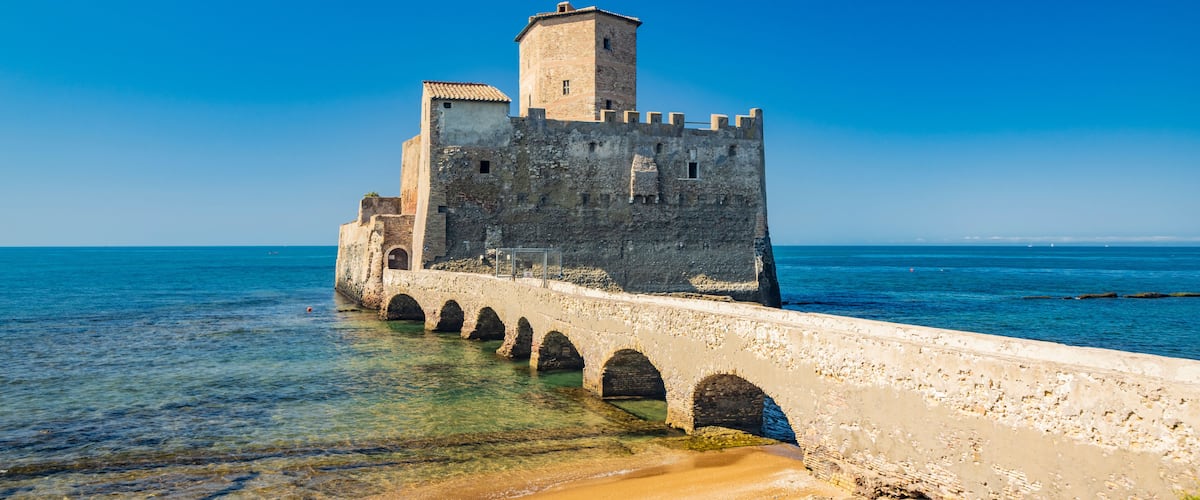 The Torre Astura nature reserve, in Nettuno. The ancient castle on the sea, with the watchtower and the remains of ancient Roman buildings. A stone bridge connects the castle to the beach.