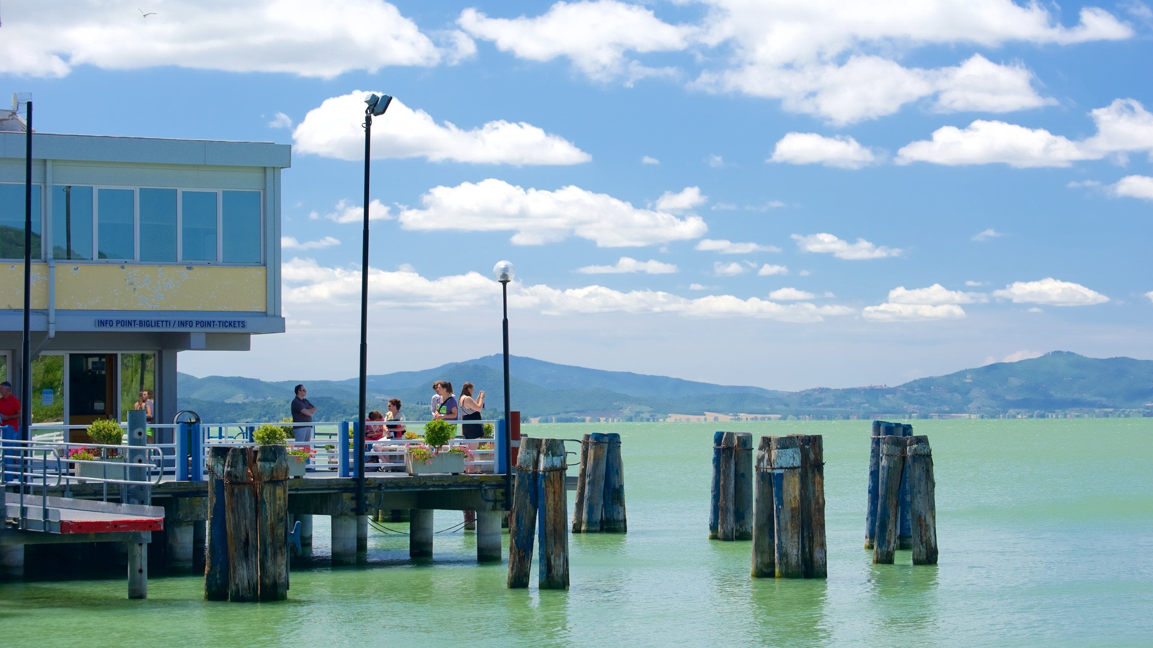 A pier with people and a building labeled "INFO POINT-BIGLIETTI / INFO POINT-TICKETS".