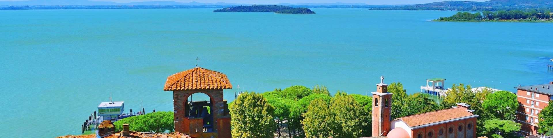Un pueblo costero con edificios de tejados terracota, una torre de campanas y una vista despejada del mar.