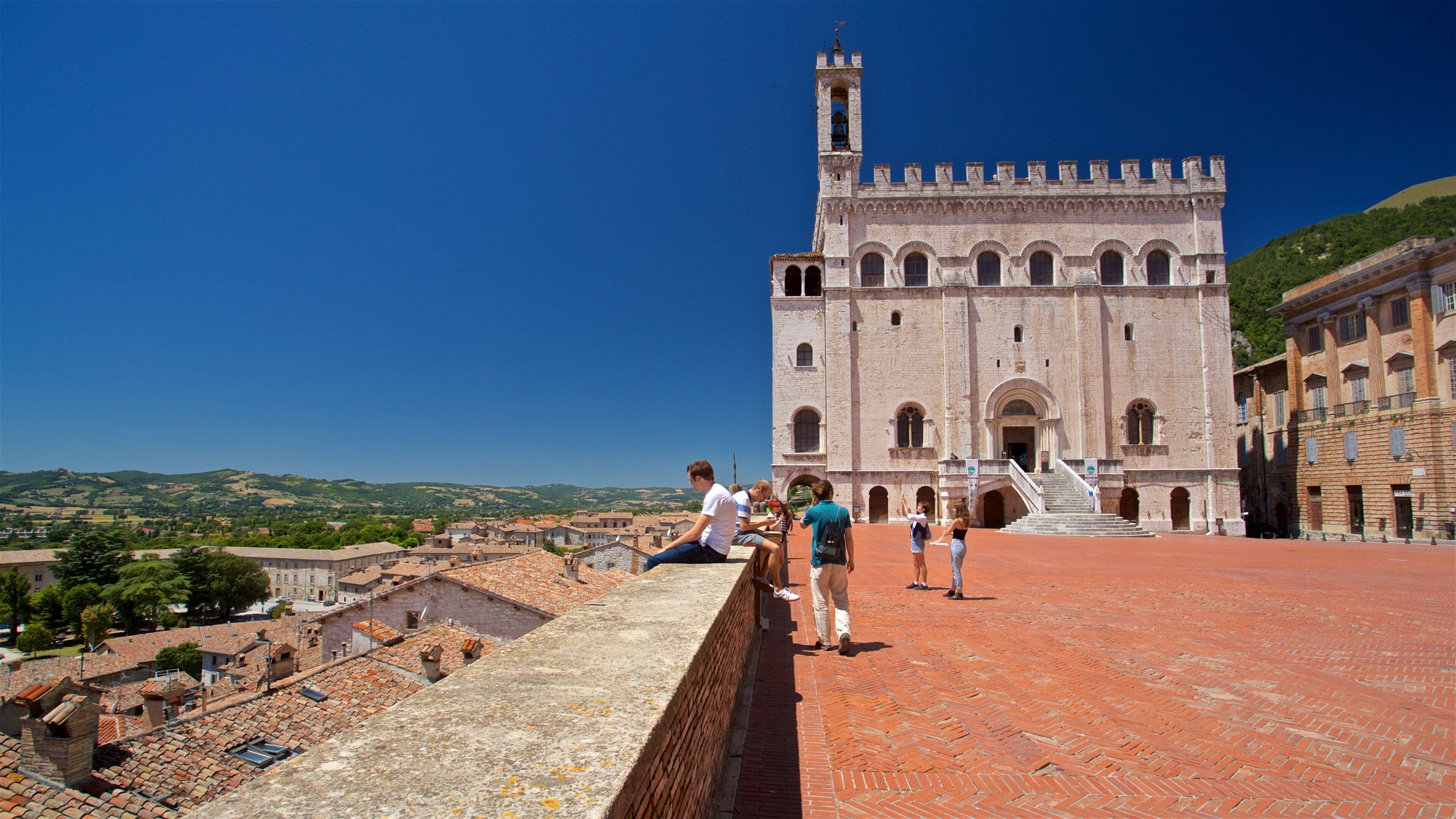 A historic building with a bell tower, a red-tiled roof, and a view of the surrounding landscape.