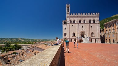 Un edificio histórico con una torre de campanas, techo de tejas rojas y vistas del paisaje circundante.