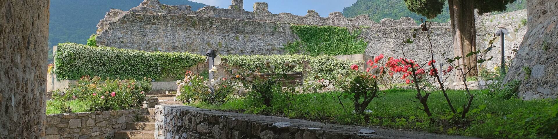 A stone pathway leading to a historic stone building with a garden in front.