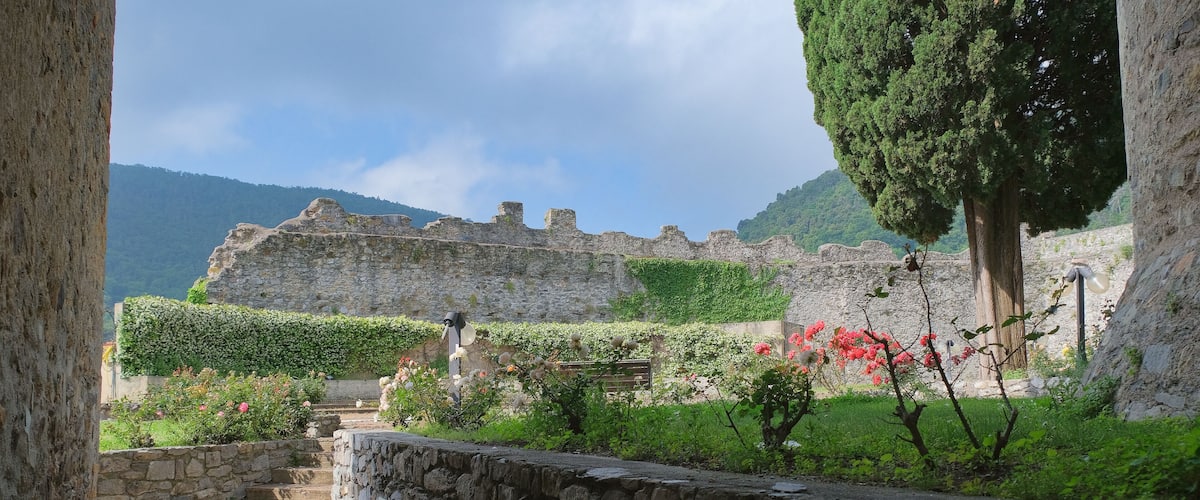 A stone pathway leading to a historic stone building with a garden in front.